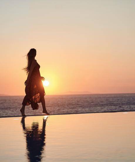 A young woman walking at the pool side during sunset