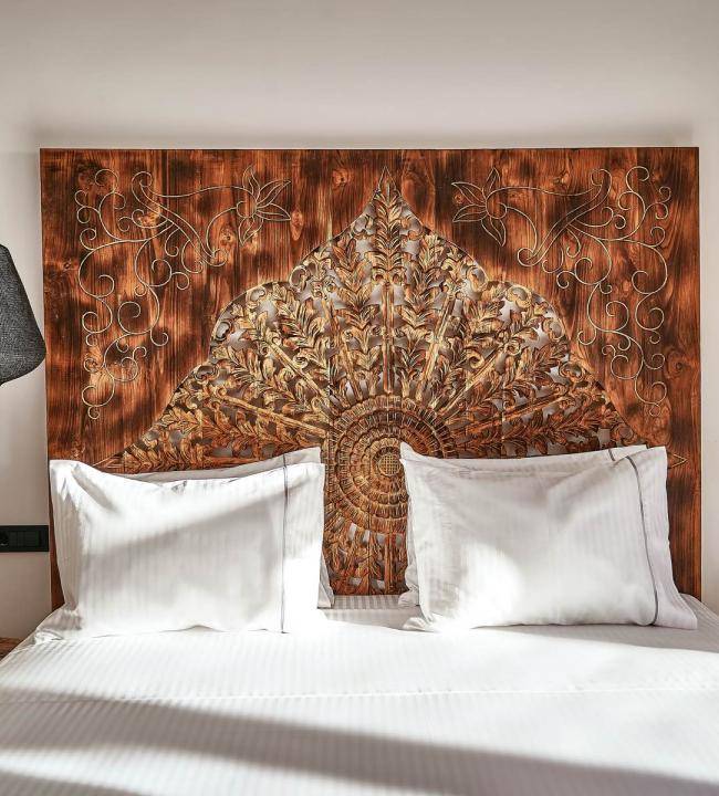 The detailed carved wood headboard in the UBUD Mykonos Deluxe room