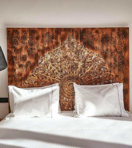 The impressive carved wood headboard in the UBUD Mykonos Deluxe room