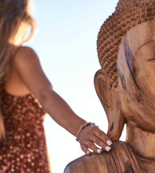 The blur picture of a woman touching a wooden Buddha statue in UBUD hotel terrace